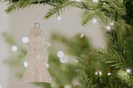 Vintage ceramic angel ornament cast from a 1976 Duncan mold, finished in a milky white mother-of-pearl glaze with subtle crystal formations, hanging on a Christmas tree