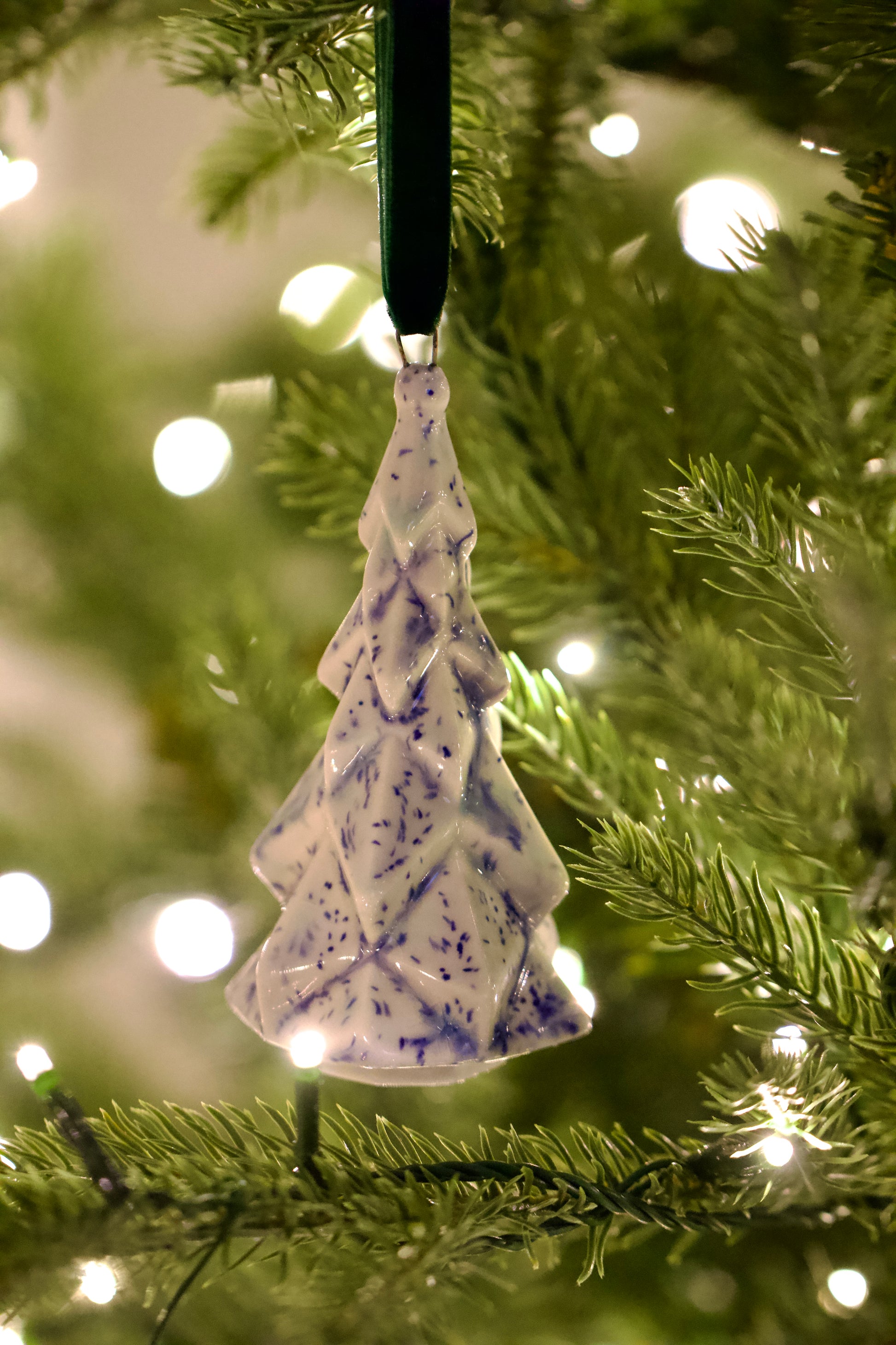 Faceted Ceramic Tree ornament with blue speckles hanging on a Christmas tree