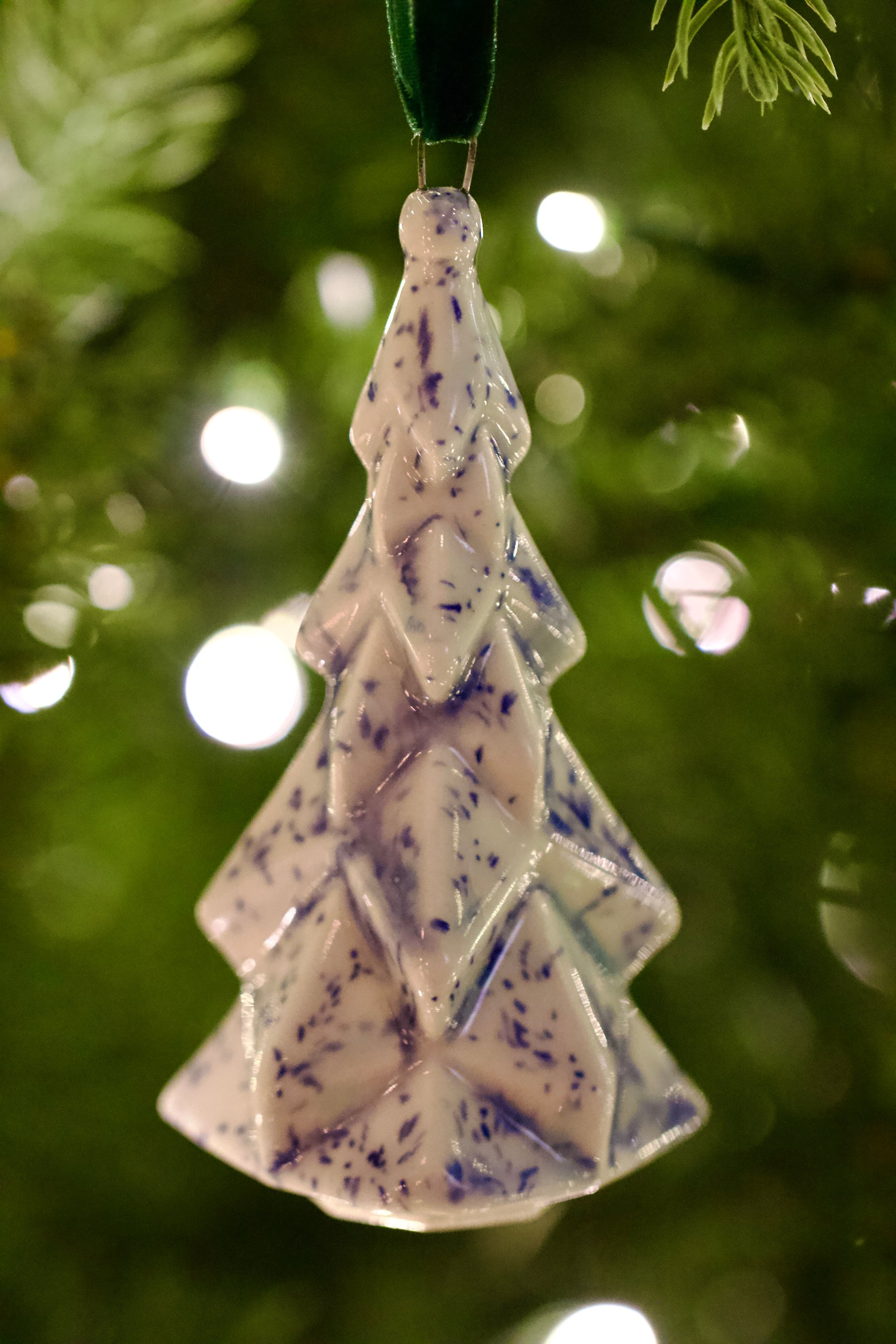 Faceted Ceramic Tree ornament with blue speckles hanging on a Christmas tree