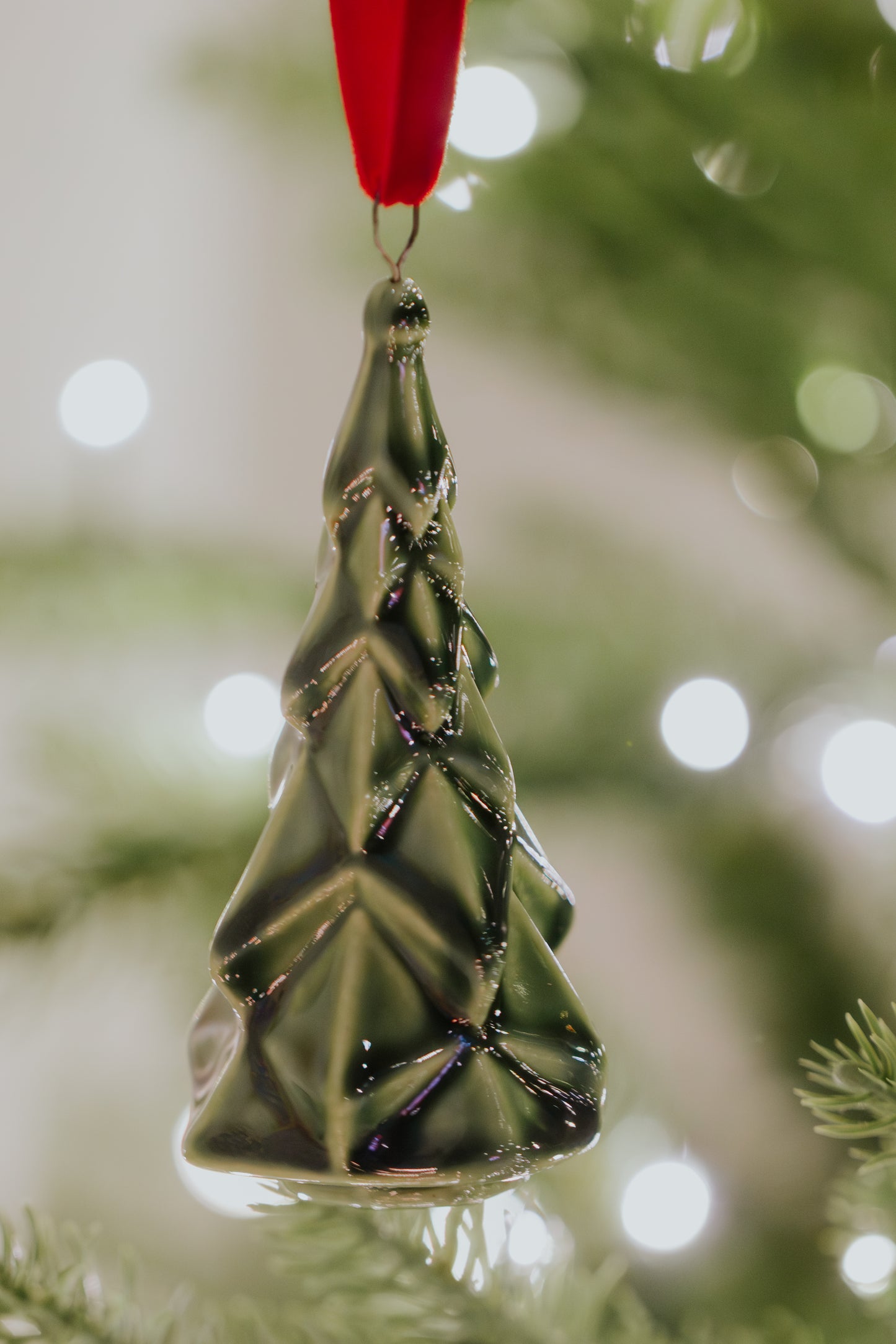 A classic green ceramic faceted Christmas tree ornament, handmade and kiln-fired for a timeless heirloom look, finished with a beautiful velvet hanger